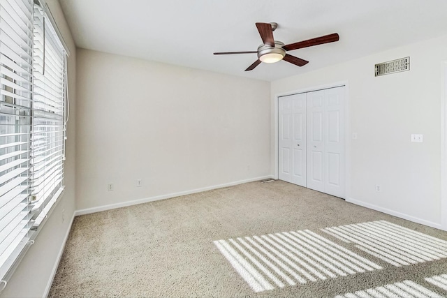 unfurnished bedroom with ceiling fan, a closet, and light colored carpet