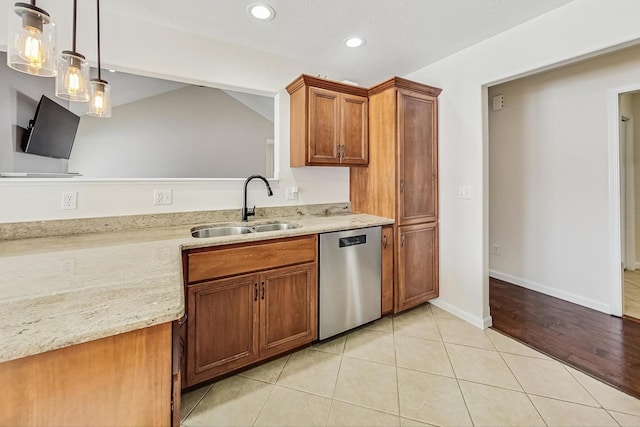 kitchen featuring light stone countertops, stainless steel dishwasher, sink, hanging light fixtures, and light tile patterned floors