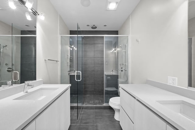 bathroom with a shower with shower door, toilet, vanity, and tile patterned flooring