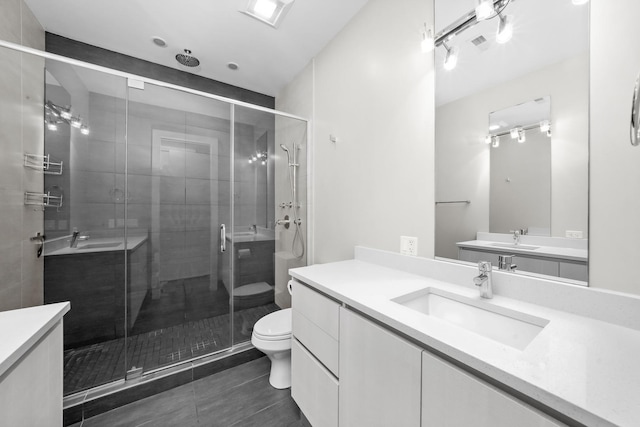 bathroom featuring toilet, vanity, tile patterned flooring, and a shower with door