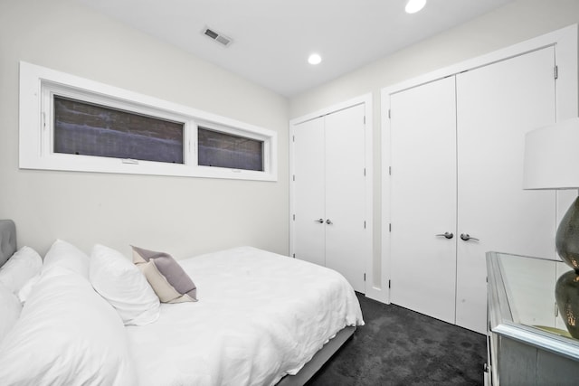 bedroom featuring multiple closets and dark carpet