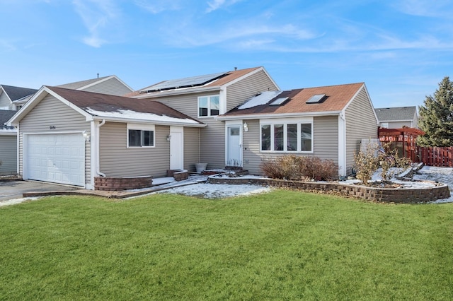 view of front of property featuring a garage, a front yard, and solar panels