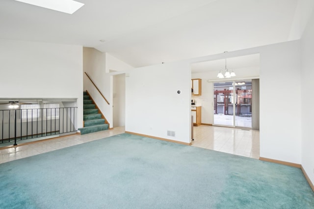 empty room featuring light carpet, vaulted ceiling with skylight, and a notable chandelier