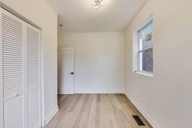 unfurnished bedroom featuring baseboards, a closet, visible vents, and light wood-style floors