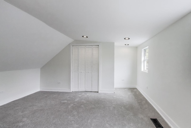 interior space featuring carpet, a closet, visible vents, baseboards, and lofted ceiling