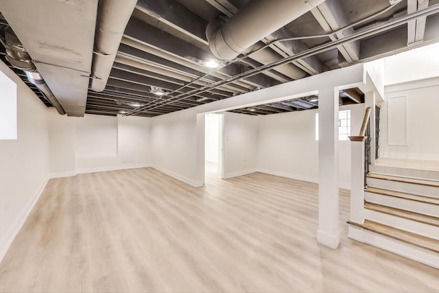 below grade area featuring light wood finished floors, stairs, and baseboards
