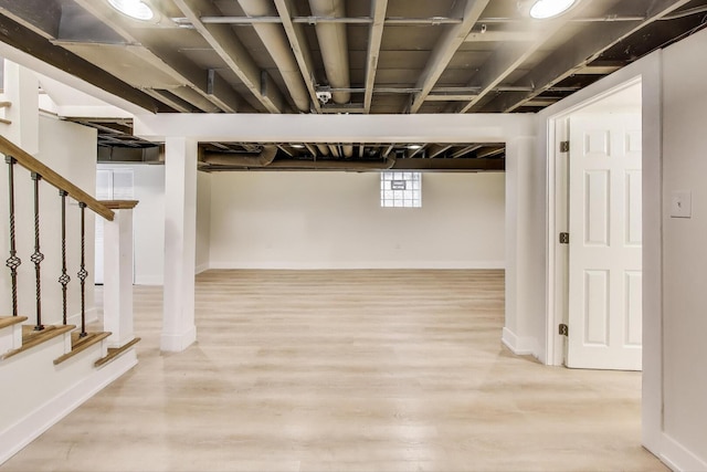 below grade area featuring wood finished floors, baseboards, and stairs