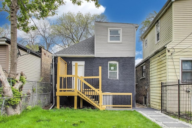 rear view of house featuring a lawn, a shingled roof, and fence