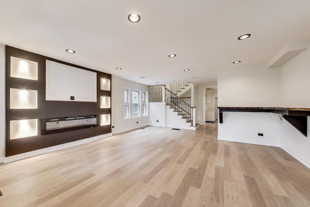 unfurnished living room featuring stairs, visible vents, baseboards, light wood-style floors, and recessed lighting