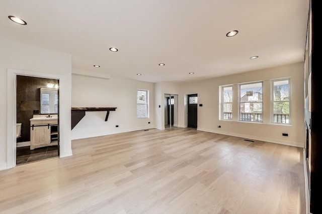 unfurnished living room featuring baseboards, light wood-style floors, visible vents, and recessed lighting
