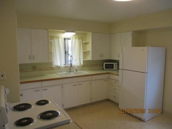 kitchen featuring white cabinetry, sink, and white appliances