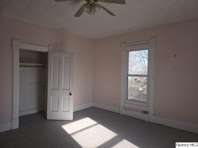 unfurnished bedroom with dark wood-type flooring, a closet, and ceiling fan