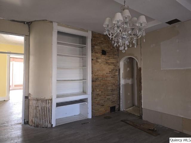 interior space featuring wood-type flooring, a chandelier, and built in features