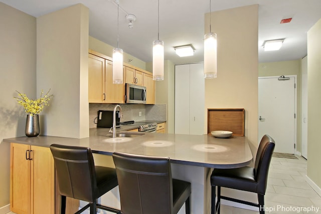 kitchen featuring a kitchen bar, light tile patterned floors, tasteful backsplash, and light brown cabinets