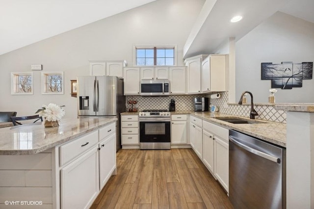 kitchen featuring a sink, stainless steel appliances, lofted ceiling, and tasteful backsplash