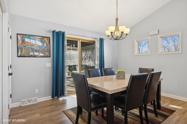 dining room featuring an inviting chandelier, dark wood-type flooring, visible vents, and vaulted ceiling