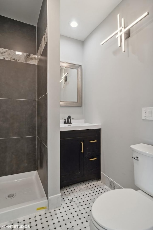 bathroom featuring toilet, tiled shower, and vanity