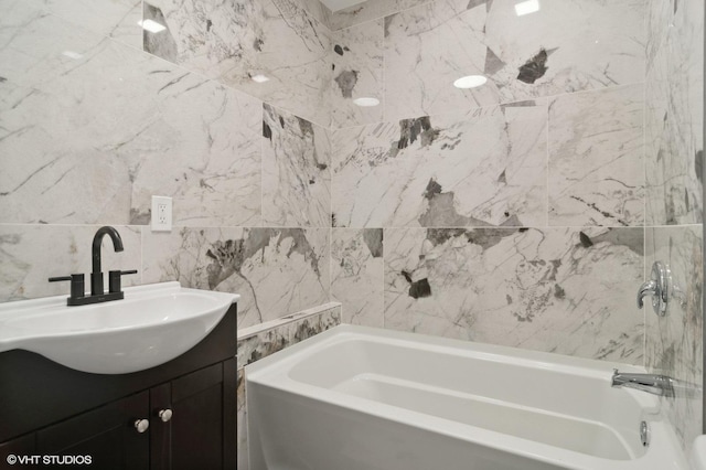 bathroom with a bathtub, vanity, and tile walls