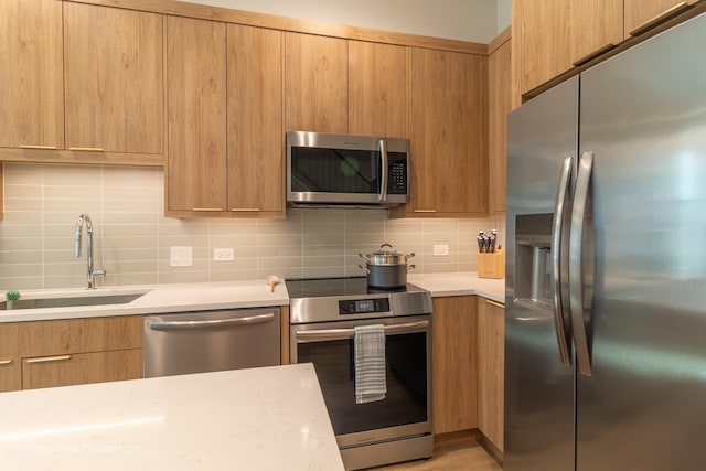 kitchen with backsplash, appliances with stainless steel finishes, and sink