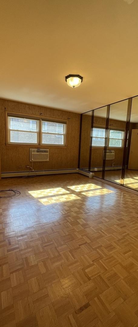 spare room with a wall unit AC, a healthy amount of sunlight, and light parquet flooring