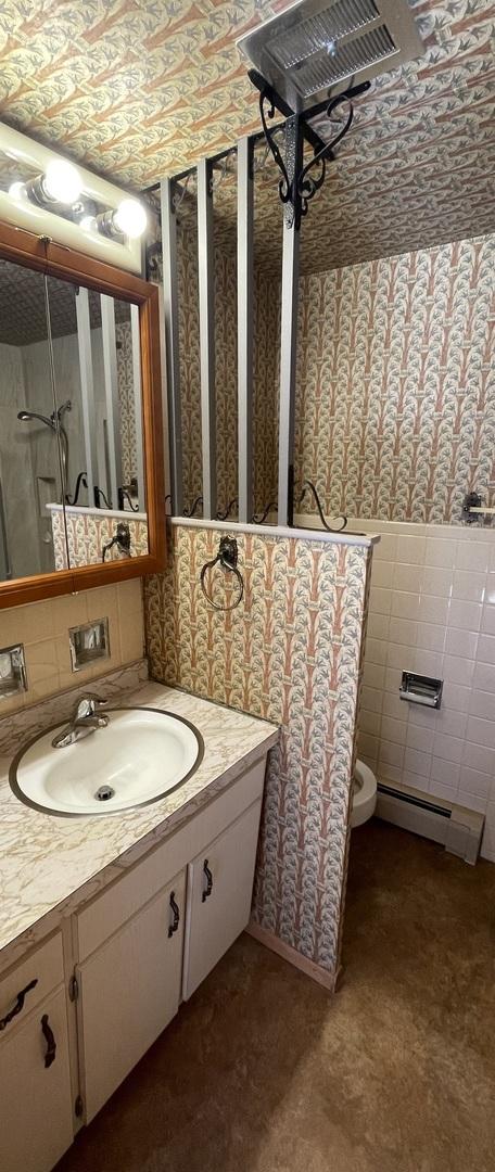 bathroom featuring baseboard heating and vanity