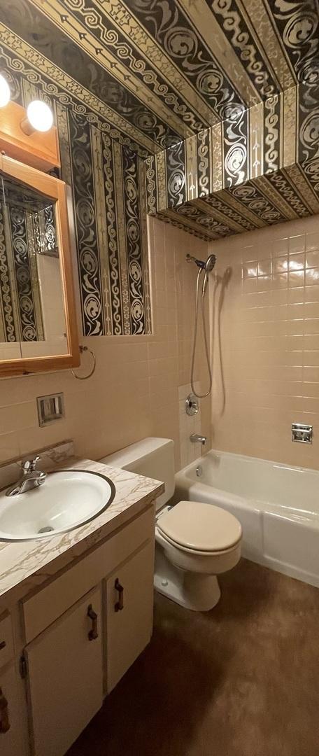 full bathroom featuring toilet, tiled shower / bath combo, and vanity