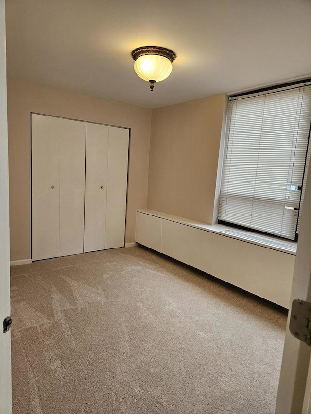 unfurnished bedroom featuring a closet and light colored carpet