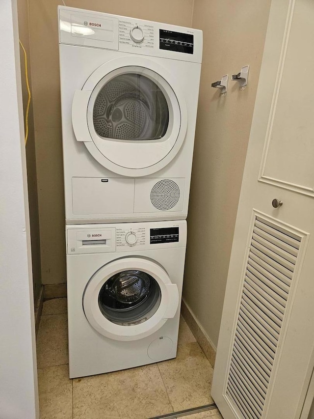 laundry area featuring light tile patterned floors and stacked washer and clothes dryer