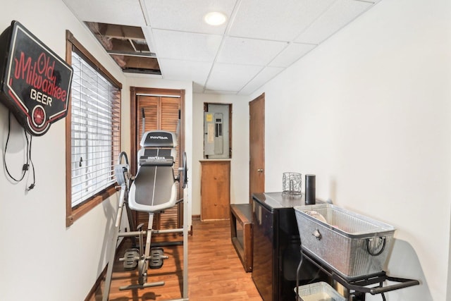 workout room with a paneled ceiling and light hardwood / wood-style floors