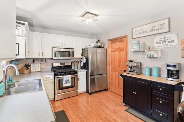 kitchen featuring sink, white cabinets, appliances with stainless steel finishes, and light hardwood / wood-style flooring