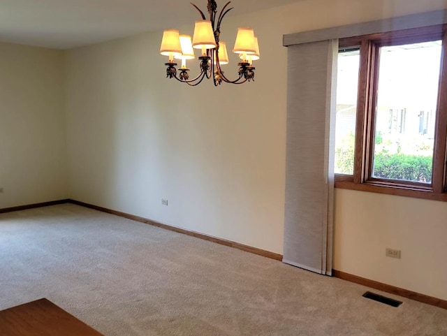 empty room with an inviting chandelier and carpet