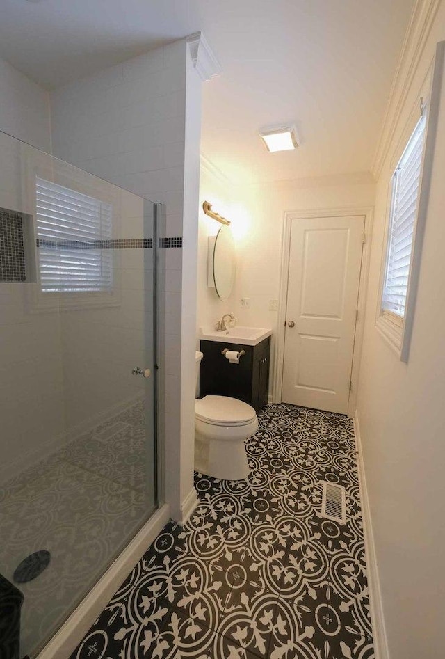 bathroom with toilet, a shower with door, tile patterned flooring, ornamental molding, and vanity