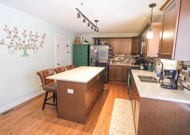 kitchen with tasteful backsplash, a kitchen island, sink, hanging light fixtures, and stainless steel appliances