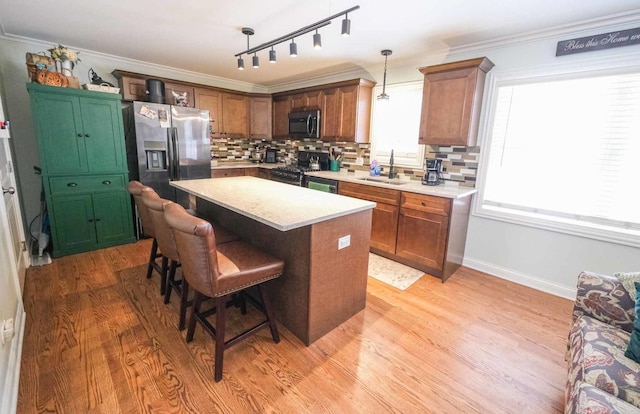 kitchen with a center island, stainless steel appliances, decorative backsplash, sink, and hanging light fixtures