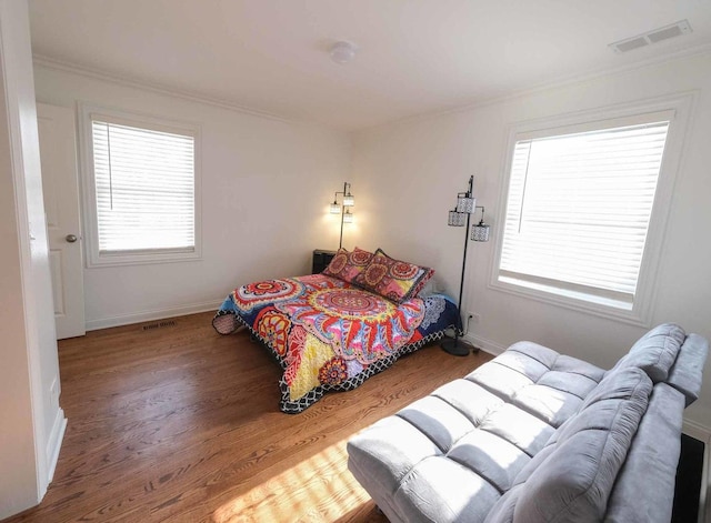 bedroom with ornamental molding, hardwood / wood-style flooring, and multiple windows