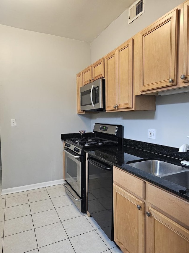 kitchen featuring dark stone countertops, sink, appliances with stainless steel finishes, light brown cabinets, and light tile patterned floors