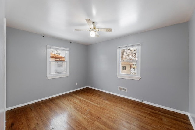 spare room featuring ceiling fan, a wealth of natural light, and wood-type flooring