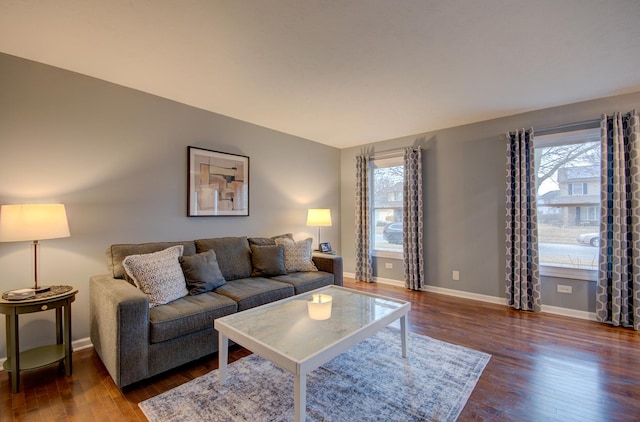 living area featuring lofted ceiling, dark wood-type flooring, and baseboards