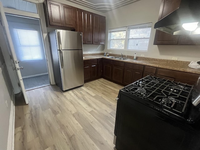 kitchen with exhaust hood, light wood-type flooring, stainless steel refrigerator, range with gas stovetop, and sink