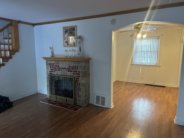 unfurnished living room featuring ceiling fan, crown molding, wood-type flooring, and a stone fireplace