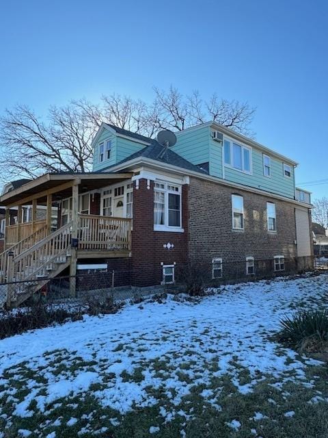 snow covered back of property featuring covered porch