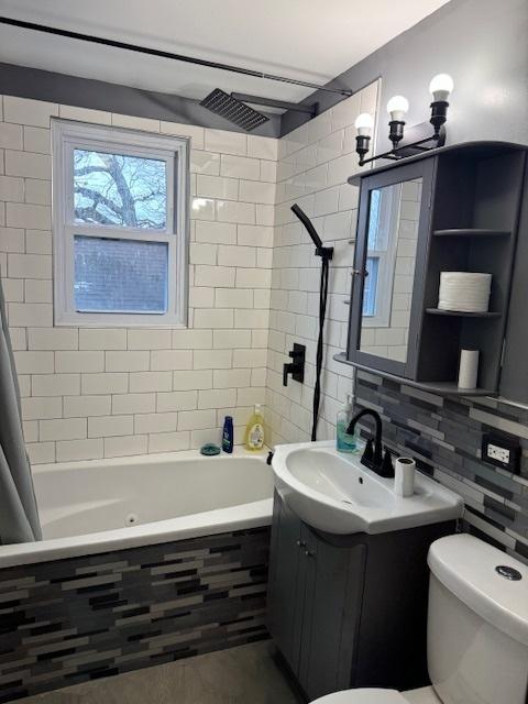 full bathroom with toilet, vanity, backsplash, tile walls, and shower / bath combo