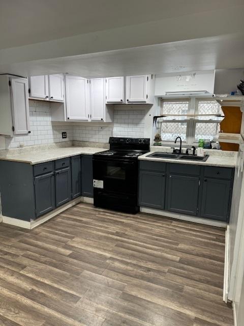 kitchen with dark wood-type flooring, white cabinetry, decorative backsplash, sink, and electric range