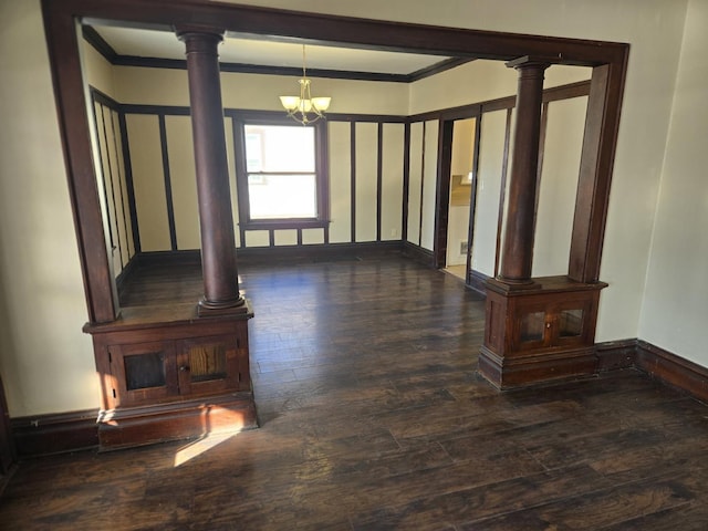 living room featuring dark hardwood / wood-style floors, an inviting chandelier, ornamental molding, and ornate columns