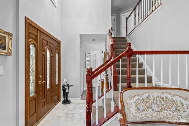 entryway with light tile patterned flooring and a towering ceiling