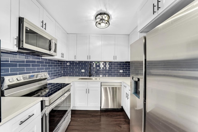 kitchen with appliances with stainless steel finishes, decorative backsplash, white cabinets, and sink