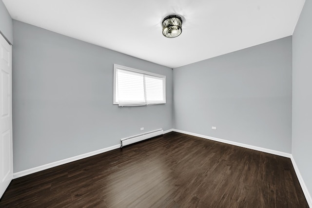 empty room with wood-type flooring and a baseboard heating unit