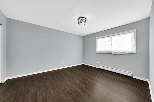 spare room featuring dark wood-type flooring and a baseboard radiator