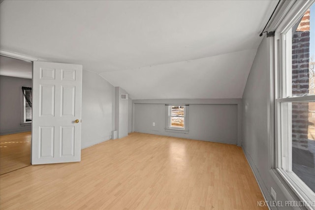 bonus room with light wood-type flooring and vaulted ceiling