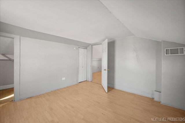 additional living space with vaulted ceiling and light wood-type flooring